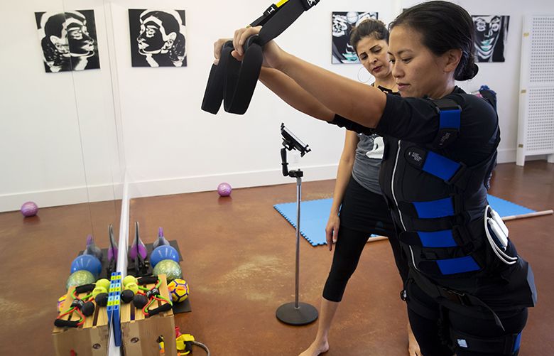 Michka Mirzanejad, owner of Body by Impulse, behind, leads an electrical muscle stimulation (EMS) workout with Nicole Tsong at her studio in the Phinney/Greenwood neighborhoods in Seattle Wednesday, Oct. 10, 2018.