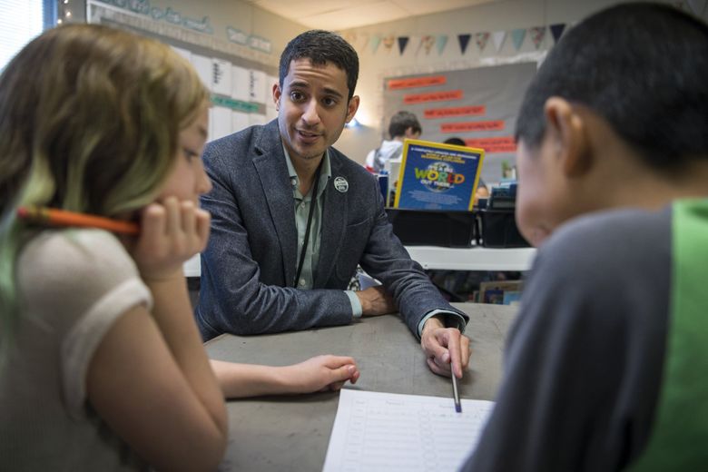 Adam Aguilera helped fourth-graders with a math game at Pioneer Elementary School. (Alisha Jucevic / The Columbian)