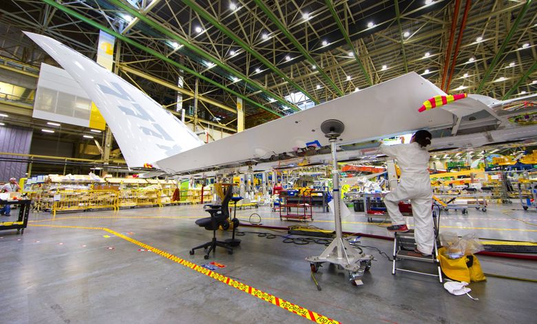 Wing mechanics work under the new 777X carbon fiber wings, the largest wings on any Boeing jet. The 11-foot wingtip folds up so that the 777X fits into all the same airports as today’s 777.  (Mike Siegel / The Seattle Times)