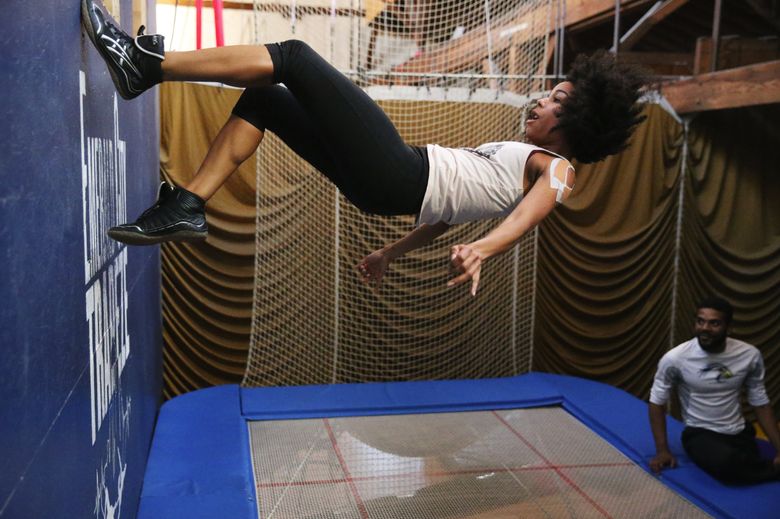 Trampoline wall student Heather Robinson, at Emerald City Trapeze class, runs upward after launching herself, Sunday, Nov. 11, 2018, in Seattle, as instructor Deon Fox looks on at right.