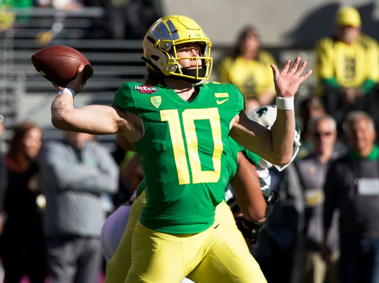 Injured Oregon quarterback Justin Herbert, left, celebrates with