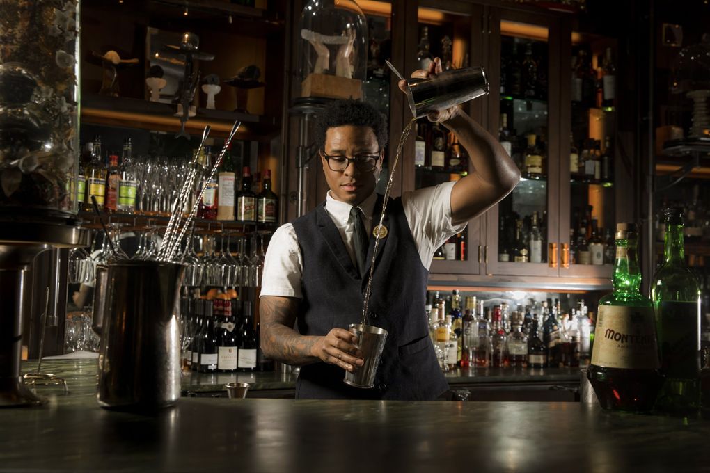 Bar manager Jermaine Whitehead pours a Trust Us cocktail featuring Del Maguey Mezcal and Amaro Montenegro at the new bar and restaurant Deep Dive underneath the Amazon Spheres. (Bettina Hansen / The Seattle Times)