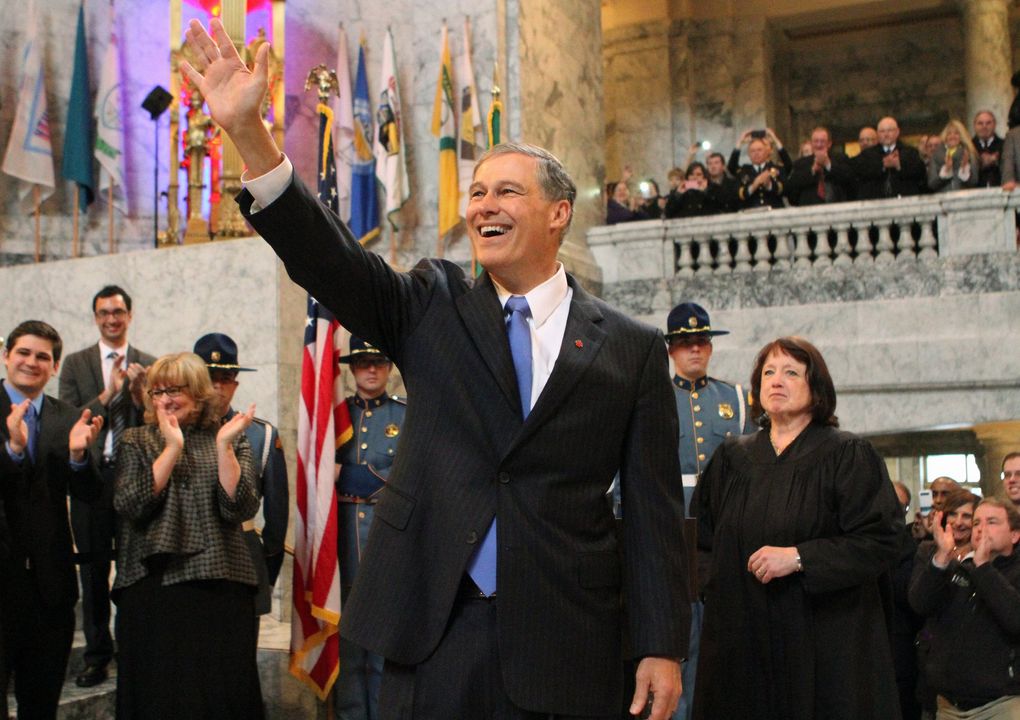 Gov. Jay Inslee waves at supporters moments after being sworn in as Washington’s 23rd governor on Jan. 16, 2013, in Olympia. Chief Justice of the Washington Supreme Court Barbara Madsen, at right, conducted the oath of office. (Ken Lambert / The Seattle Times)