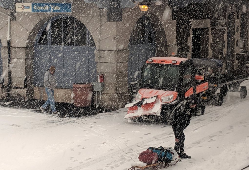 A man drags his luggage on a sled in the snow at the Klamath Falls station. (Crystal Paul / The Seattle Times)