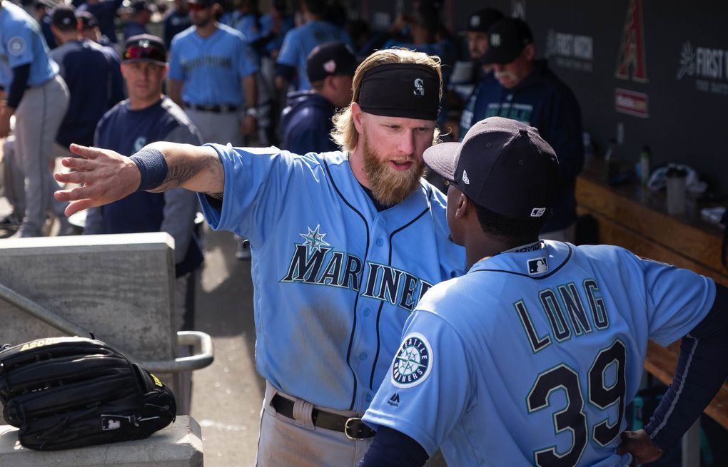 Jake Fraley and Shed Long talk hitting in the Mariner dugout Feb. 24 in Scottsdale, Ariz. (Dean Rutz / The Seattle Times)