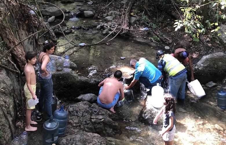 Venezuelans fill bottles with water from the Sabas Nieves creek in Eastern Caracas. Families that can afford to drive go are taking water from natural sources. MUST CREDIT: Washington Post photo by Arelis Hernandez