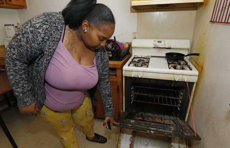 In this Feb. 20, 2019 photo, Destiny Johnson shows the broken door to her oven that she uses string to hold together, in her apartment in Cedarhurst Homes, a federally subsidized, low-income apartment complex in Natchez, Miss. The complex failed a health and safety inspection in each of the past three years. Upset with conditions, Johnson moved out in late March. (AP Photo/Rogelio V. Solis) MSRS501 MSRS501