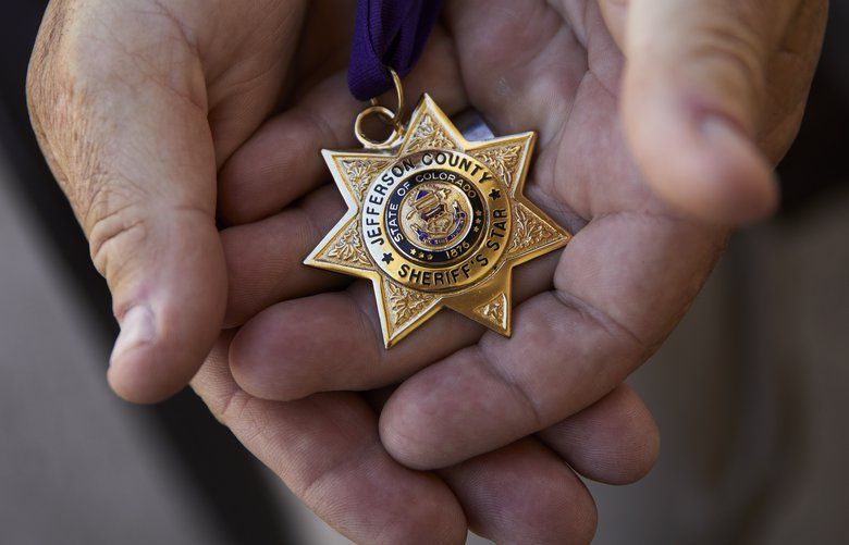 In this April 9, 2019, photo, Grant Whitus holds the Jefferson County Sheriff’s Star at his home in Lake Havasu City, Ariz. Whitus received the award for his actions on several incidents while with the Jefferson County Regional SWAT team, including Columbine High School. Whitus’ marriage fell apart a year after he led his SWAT team into Columbine High School’s library, where he was the first to find the dead children’s bodies. (AP Photo/John Locher) NVJL204 NVJL204