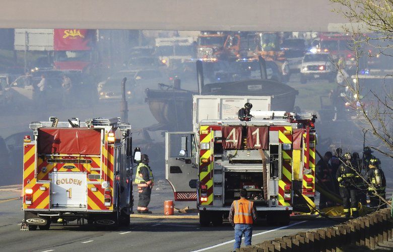In this Thursday, April 25, 2019 photo, emergency crews work at the scene of a deadly collision on Interstate 70 near the Colorado Mills Parkway in Lakewood, Colo. On Friday, police said the truck driver blamed for causing the fatal pileup involving over two dozen vehicles has been arrested on vehicular homicide charges. (Hyoung Chang/The Denver Post via AP) CODEN102 CODEN102