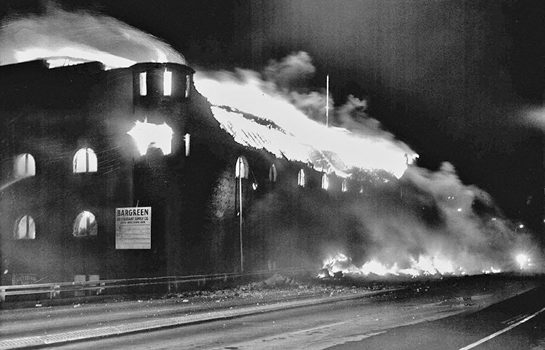 (OLD ORIGINAL CAPTION) Armory Afire: Flames swept through the roof of the old Armory early yesterday. Burning debris lay on the damaged Northbound lanes of the Alaskan Way Viaduct. (NEW CAPTION TO COME FROM PAUL DORPAT?)