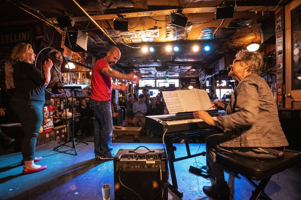 Marcus Shelton takes a bow after performing at the Blue Moon tavern, and recognizes accompanist Rhonda Kline. At left is Kimberly Giordano. (Dean Rutz / The Seattle Times)