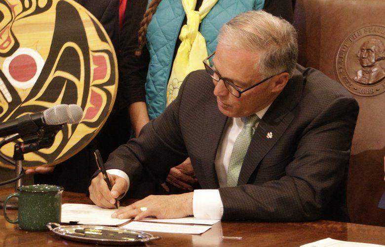 Washington Gov. Jay Inslee, surrounded by lawmakers, tribal members and others, signs the first of several bills designed to help the Pacific Northwest’s endangered orcas on Wednesday, May 8, 2019, in Olympia, Wash. The measures include requiring more oil shipments to have tugboat escorts to prevent spills, allowing anglers to catch more walleye and bass that prey on young salmon, and giving state agencies the authority to ban toxic chemicals in consumer goods. (AP Photo/Rachel La Corte) RPRL105 RPRL105