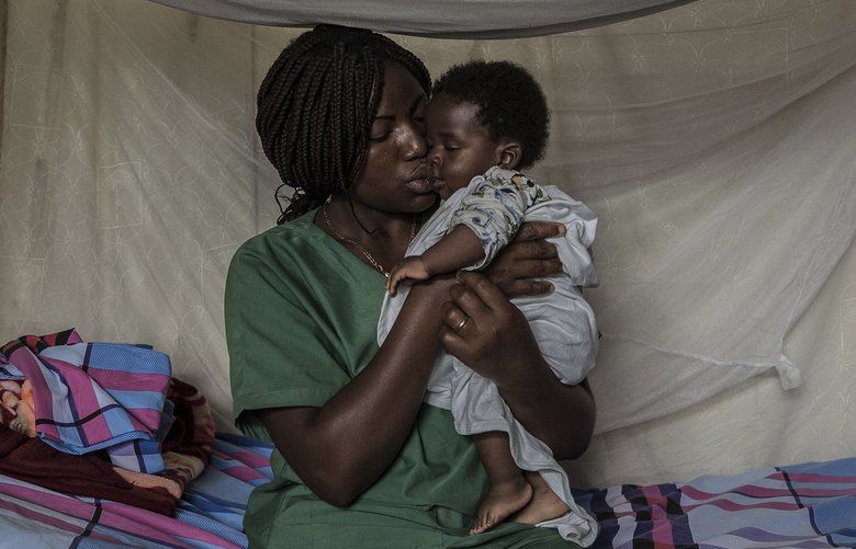 An Ebola survivor who is now immune to the virus holds a child whose mother was being tested at an Ebola treatment center in Beni, Congo, May 7, 2019. An Ebola outbreak in eastern Congo — the second-largest in history — is escalating in part because locals don’t trust health workers and government officials. (Finbarr O’Reilly/The New York Times) XNYT94 XNYT94