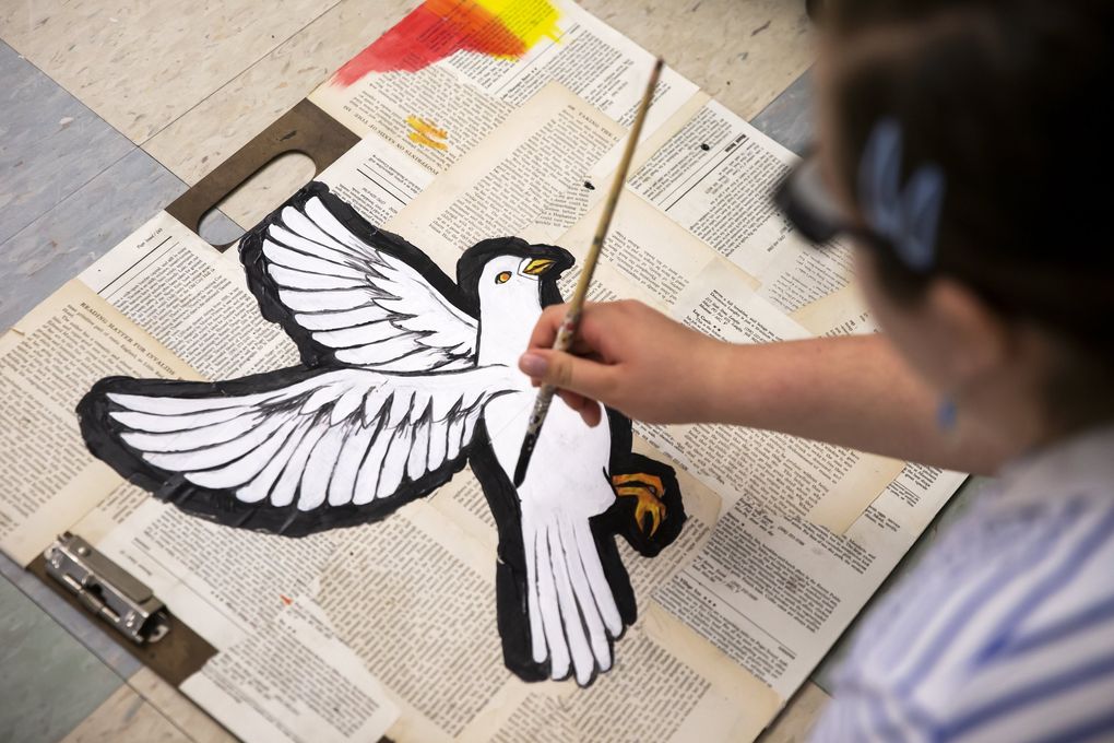 Alexandra Lawson-Mangun, 16, a Franklin High School sophomore, paints a white dove as part of the set for the play “Don’t Call it a Riot!” (Bettina Hansen / The Seattle Times)
