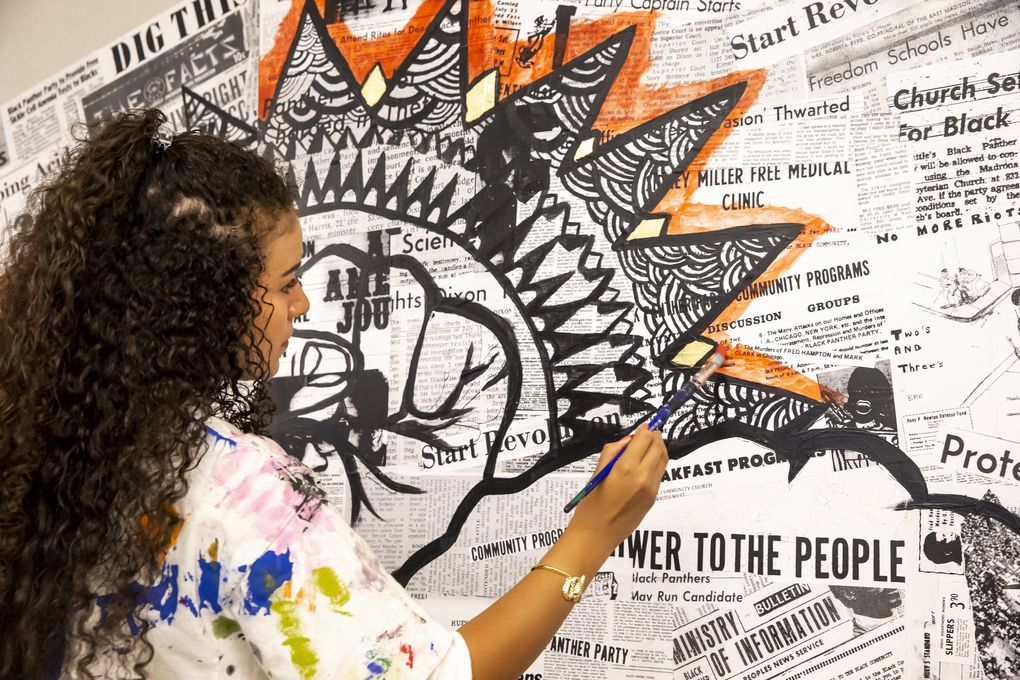Franklin High School senior Veronique Harris, 18, paints a mixed-media mural that will be part of the set of “Don’t Call it a Riot!” by Seattle playwright Amontaine Aurore. (Bettina Hansen / The Seattle Times)