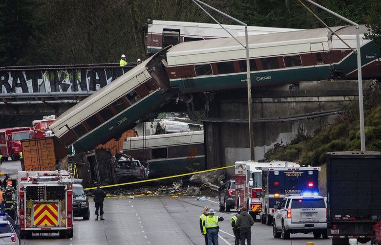 A car at left center on an Amtrak southbound train appears to be resting on an overturned train car that is laying in the southbound lanes of I-5 after the train derails south of Mounts Road SW overpass  Monday morning, December 18, 2017.