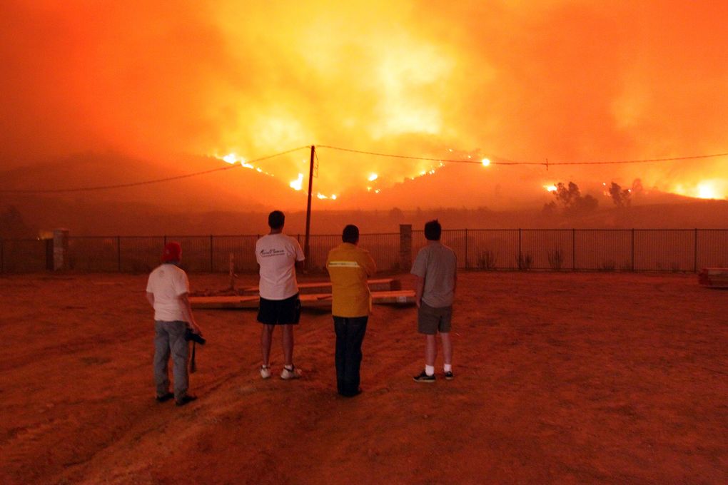 In this Nov. 15, 2008, photo, residents look on as a wind-driven Santa Ana fire threatens homes in Yorba Linda, Calif. (AP Photo/Richard Vogel, File)