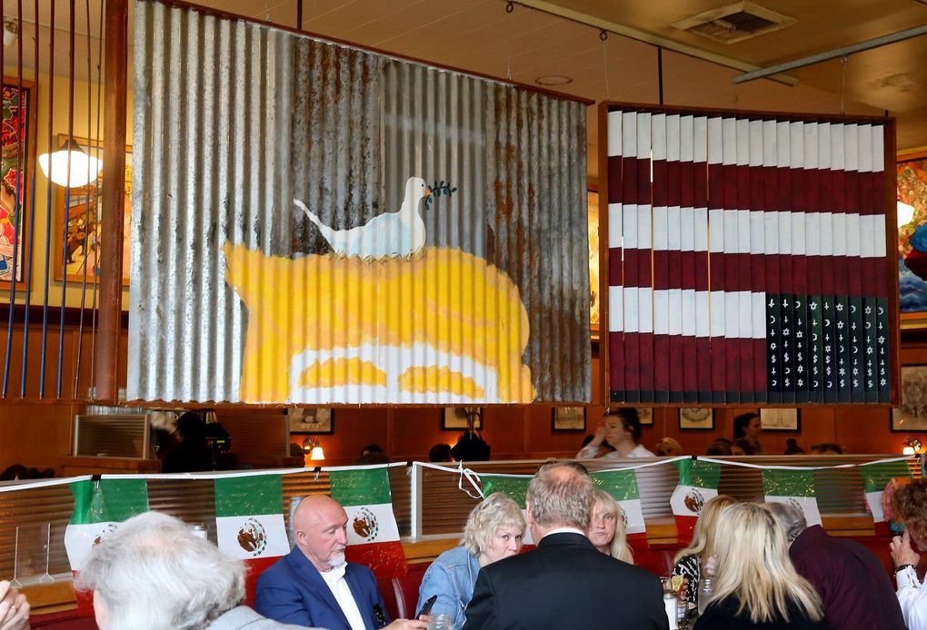 To underscore its support of immigrants, The 5 Spot built a wall — three panels bearing topical artwork now divide the bar from the dining room. At left, with bird: “Trump’s Folly” by Mark Silver. (Greg Gilbert / The Seattle Times)