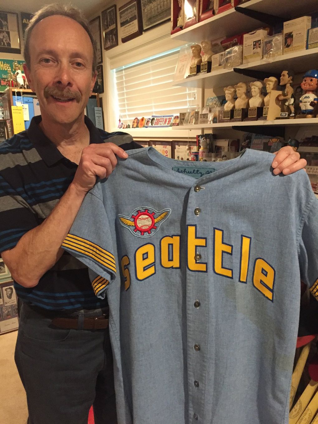 Charles Kapner in his memorabilia room holding the road uniform of Pilots manager Joe Schultz. (Larry Stone / The Seattle Times)