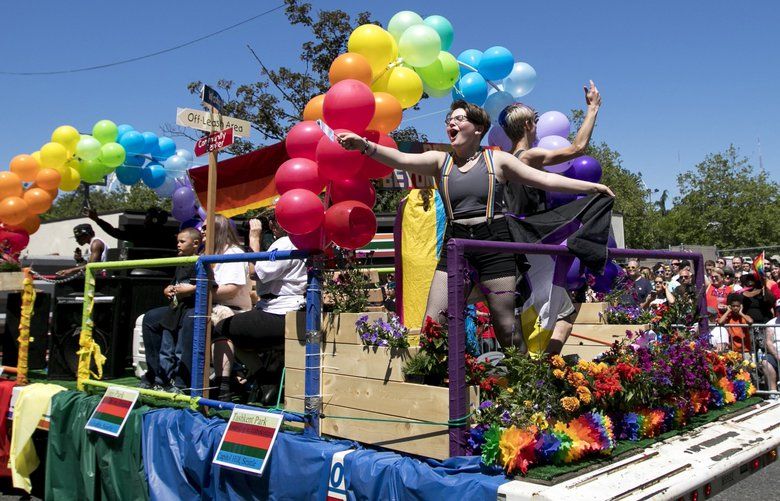 Ceridwen Books, left, and Devin Johnson dance on a float pulled by one of Seattle Parks and Recreation’s dump trucks at the Seattle Pride Parade in Downtown Seattle Sunday June 24, 2018. 206776 206776