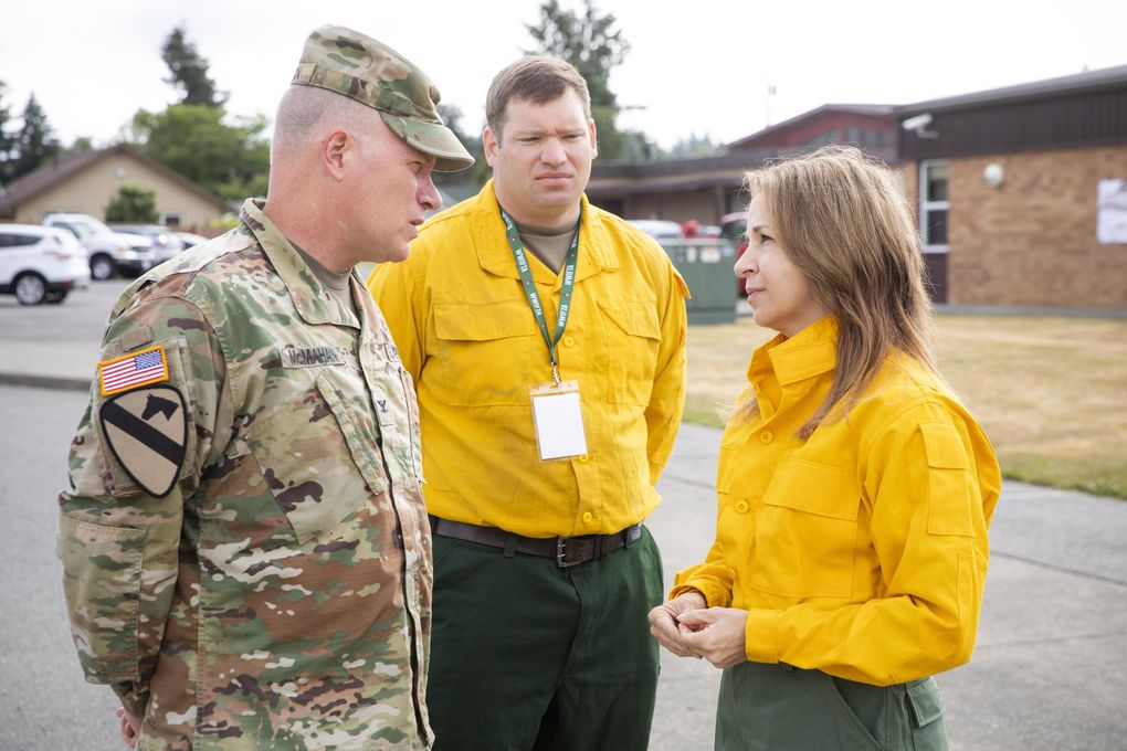Hilary Franz, Washington state commissioner of public lands, talks with Col. Kevin McMahan, left, of the Washington National Guard, and Marco Brettmann, interagency representative between the National Guard and the state Department of Natural Resources, at the Western Washington Interagency Wildfire Training Academy in Rainier, Thurston County. The Washington National Guard has ramped up its participation in the academy. (Bettina Hansen / The Seattle Times)