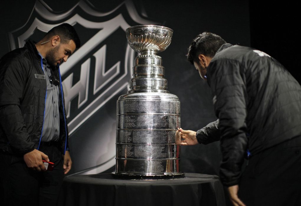 Security personnel examine the Stanley Cup on display during the second day of the NHL draft last weekend in Vancouver, British Columbia. (Chad Hipolito/The Canadian Press via AP)