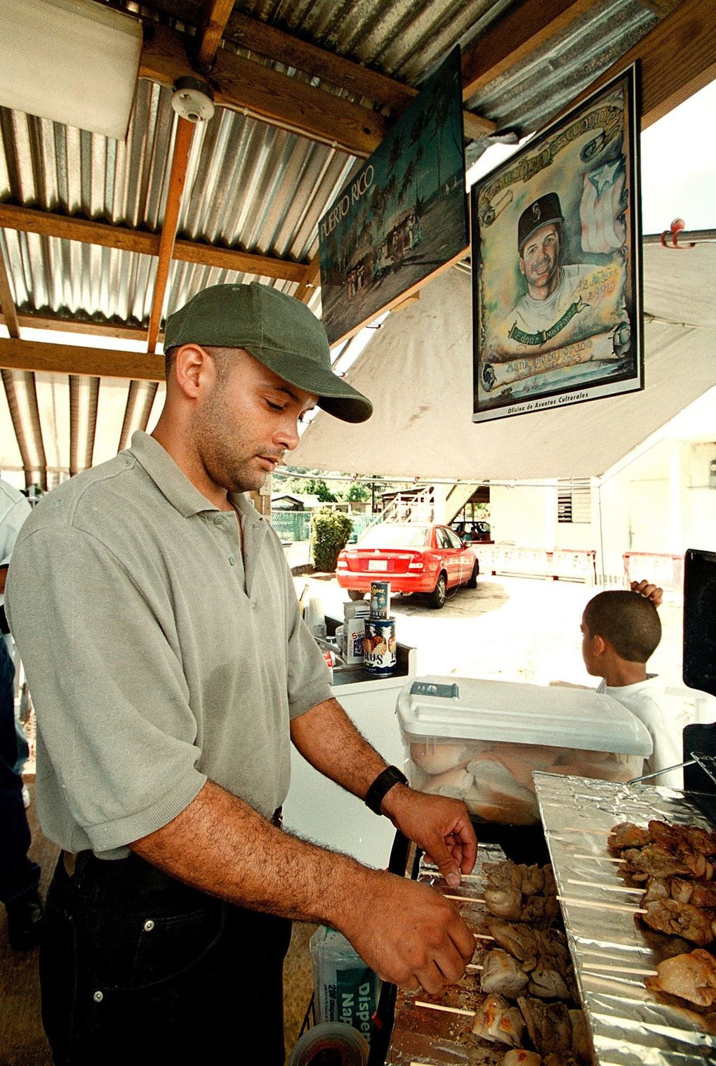 Jose Santana prepares the traditional Puerto Rican “Pinchos” made of pork and chicken. In the background a painting of Edgar Martinez has a special place in his shop. (Juan Luis Martinez / Special for The Seattle Times)