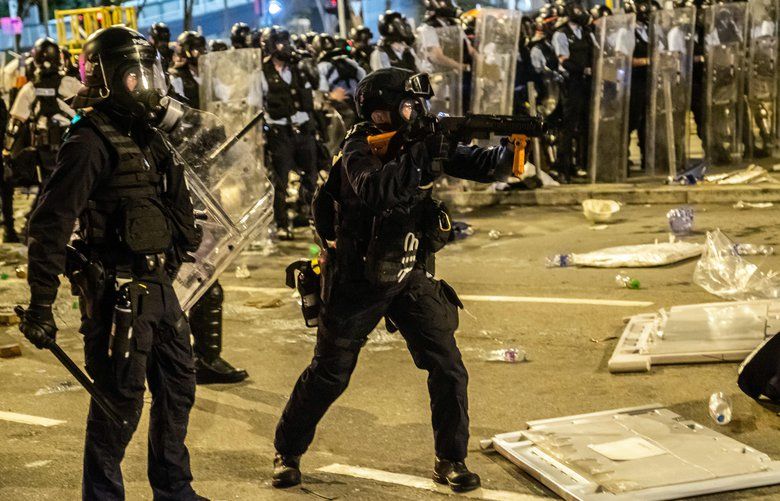 A riot police officer prepares to fire tear gas at protesters outside the Legislative Council in Hong Kong shortly after midnight on Tuesday morning, July 2, 2019.  Hundreds of riot police used tear gas and shields after midnight to disperse protesters near the Legislative Council, after hundreds of demonstrators stormed the offices and occupied it for three hours.  (Lam Yik Fei/The New York Times) XNYT64 XNYT64