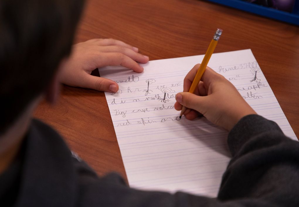 A Hamlin Robinson School fourth grader writes sentences during a lesson being taught by teacher Kay Nelson. (Mike Siegel / The Seattle Times)