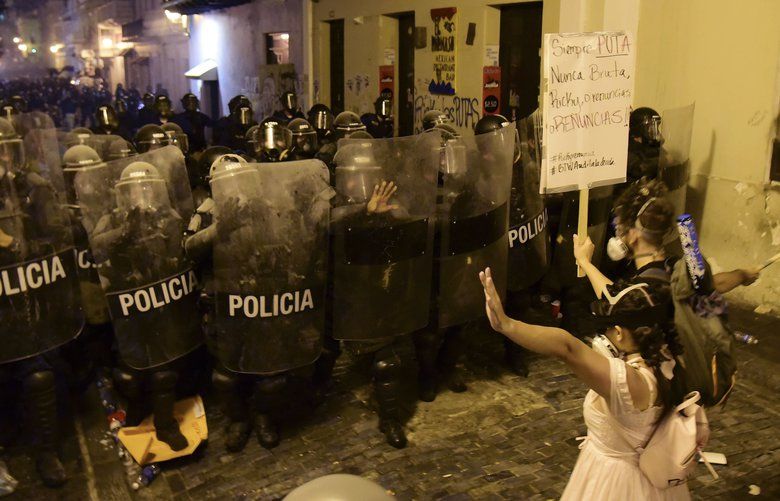 Demonstrators react in front of the police during clashes in San Juan, Puerto Rico, Wednesday, July 17, 2019. Thousands of people marched to the governor’s residence in San Juan on Wednesday chanting demands for Gov. Ricardo Rossello to resign after the leak of online chats that show him making misogynistic slurs and mocking his constituents. (AP Photo/Carlos Giusti) XRE113 XRE113