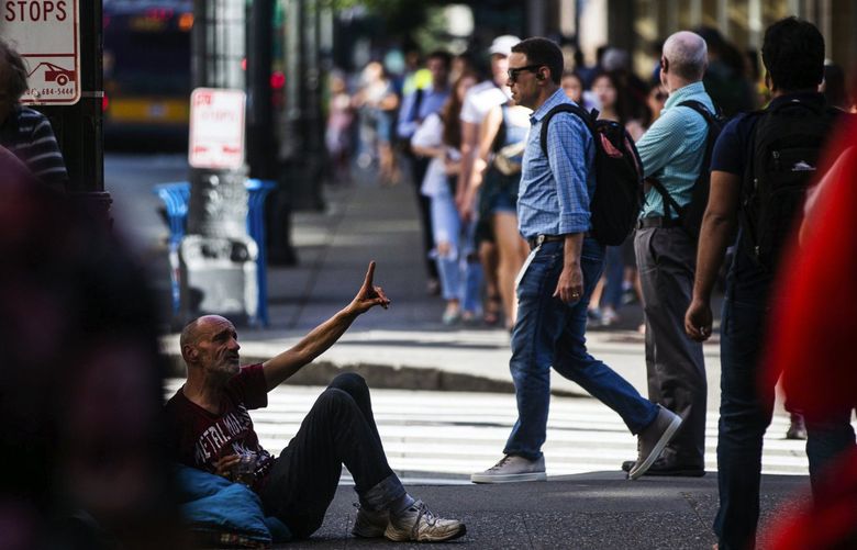 A man asks pedestrians for a dollar as crowds near a bus stop on Third Avenue in downtown Seattle on Monday, July 21. 210964 210964 (Rebekah Welch / The Seattle Times)