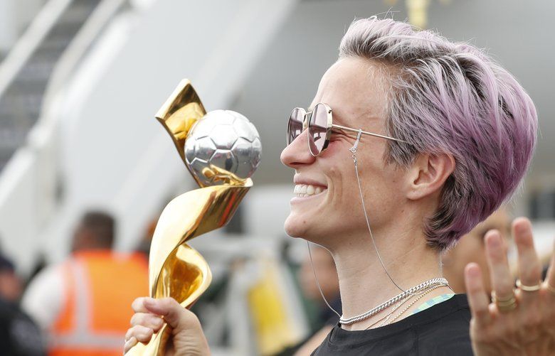 United States women’s soccer team member Megan Rapinoe holds the Women’s World Cup trophy as she poses for the media after arriving with the rest of the team at Newark Liberty International Airport, Monday, July 8, 2019, in Newark, N.J. (AP Photo/Kathy Willens) NJKW107 NJKW107