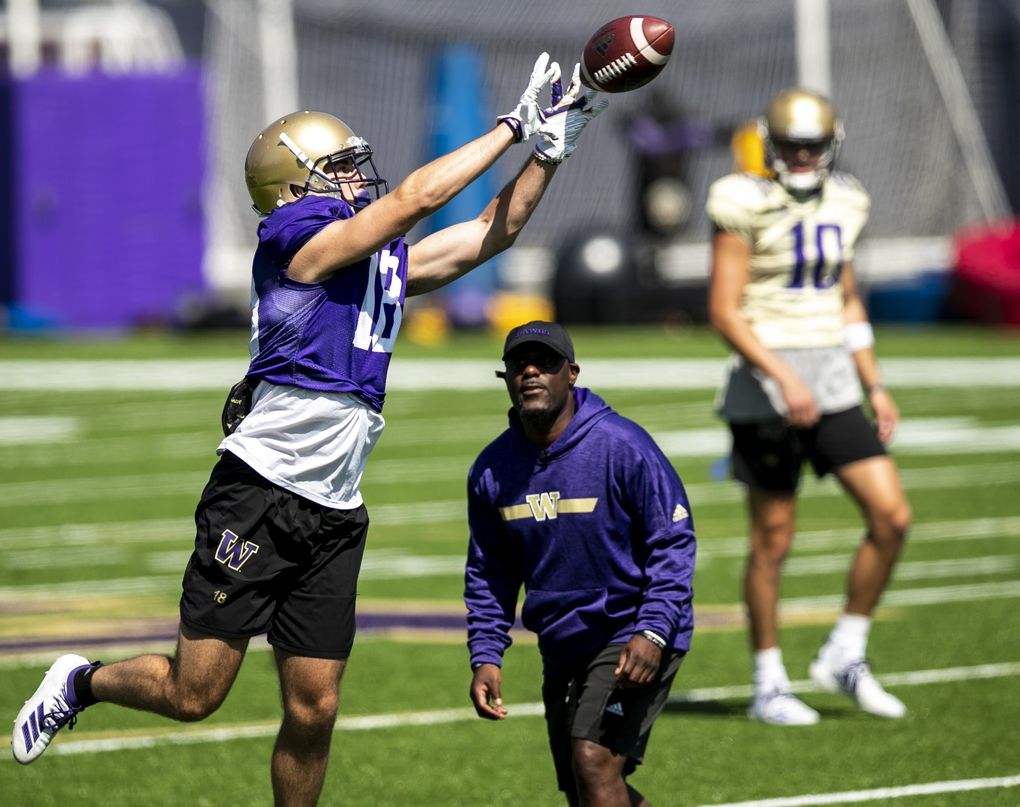 Huskies wide receiver Austin Osborne jumps up for a catch in front of Junior Adams, wide receivers coach, as the University of Washington holds day five of football training camp at Husky Stadium Tuesday August 6, 2019. (Bettina Hansen / The Seattle Times)