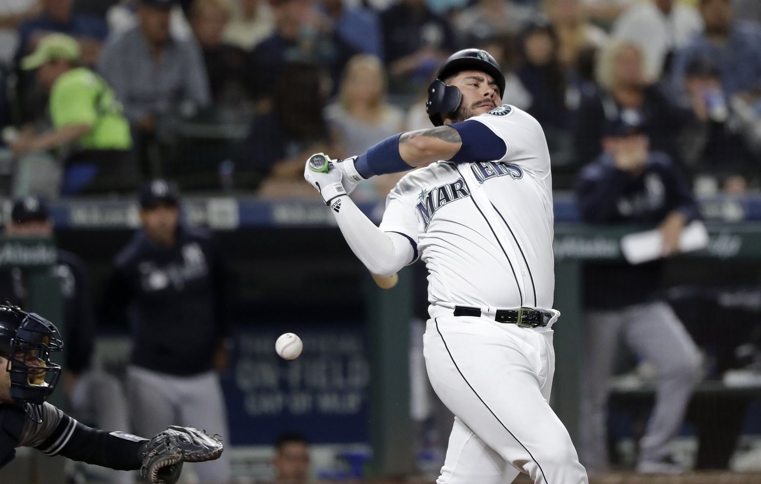 Seattle Mariners' Omar Narvaez removes his batting helmet in the dugout as  he greets teammates after hitting a three-run home run during the third  inning of a baseball game against the Boston