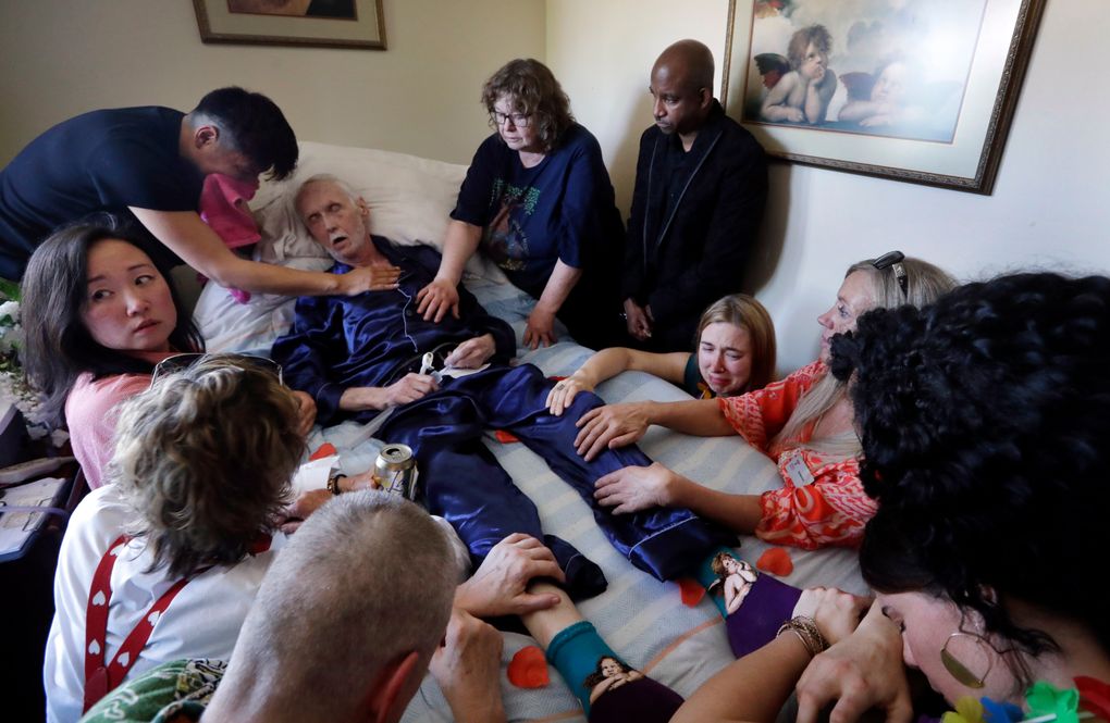 Robert Fuller lies unconscious after administering the prescribed drugs to end his life as his husband, Reese Baxter, upper left, and friends lay hands on him May 10 in Seattle.
(AP Photo/Elaine Thompson)