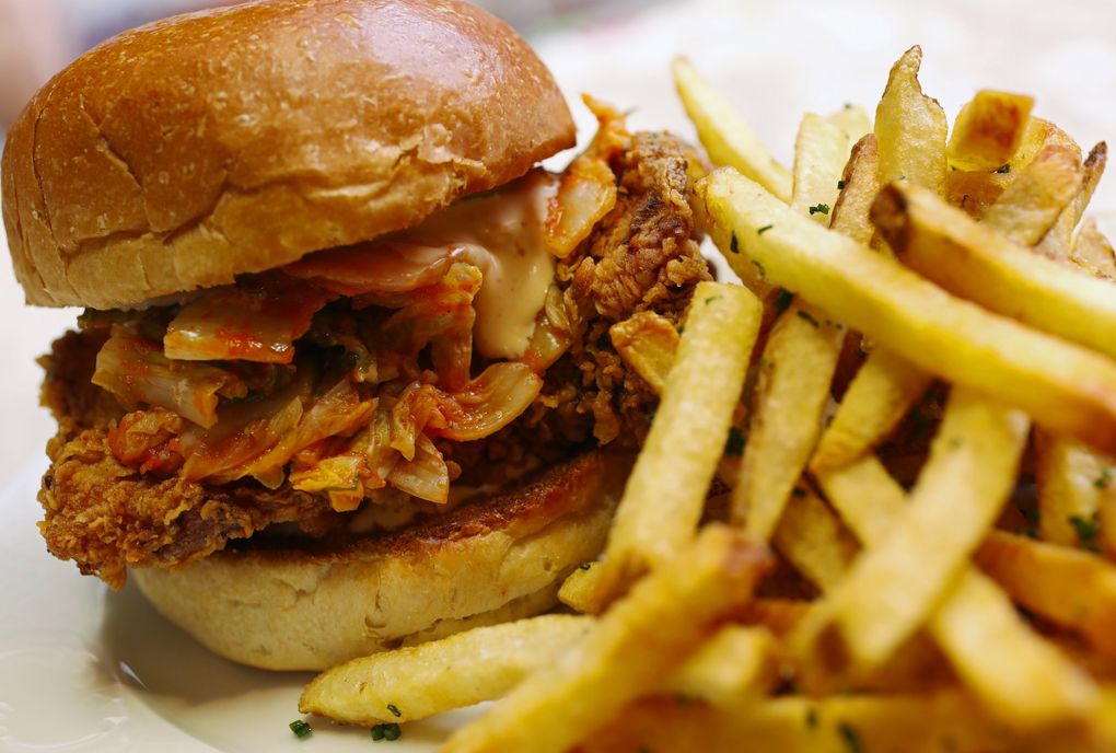 The fried-chicken sandwich at Ben Paris restaurant comes with Sriracha mayo, a house-made dill pickle, smoked paprika, cayenne peppers, Fresno chili peppers and kimchi. It may be over the top, but it works. (Ken Lambert / The Seattle Times)