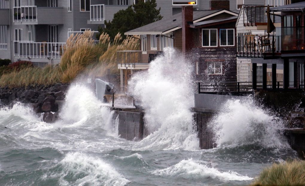 Waves smack a breakwater, sending salt spray onto homes along Puget Sound during a 2017 windstorm in Seattle. (AP Photo / Elaine Thompson, File)