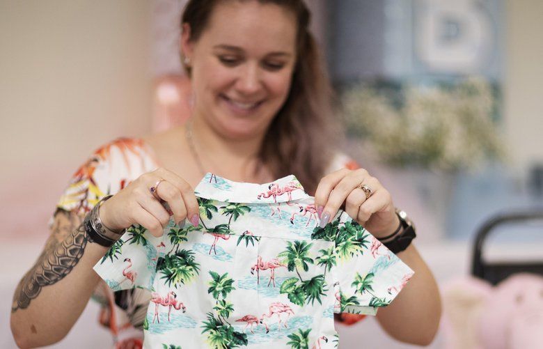 Krista Johnston looks at a tiny Hawaiian shirt given as a gift during a baby shower at the American Legion in Trumansburg, N.Y., Sunday, Sept. 1, 2019. Johnston’s husband, Sgt. James Johnston, who loved Hawaiian shirts, was killed in Afghanistan in June just months after learning he would become a father. (AP Photo/David Goldman) NYDG201 NYDG201