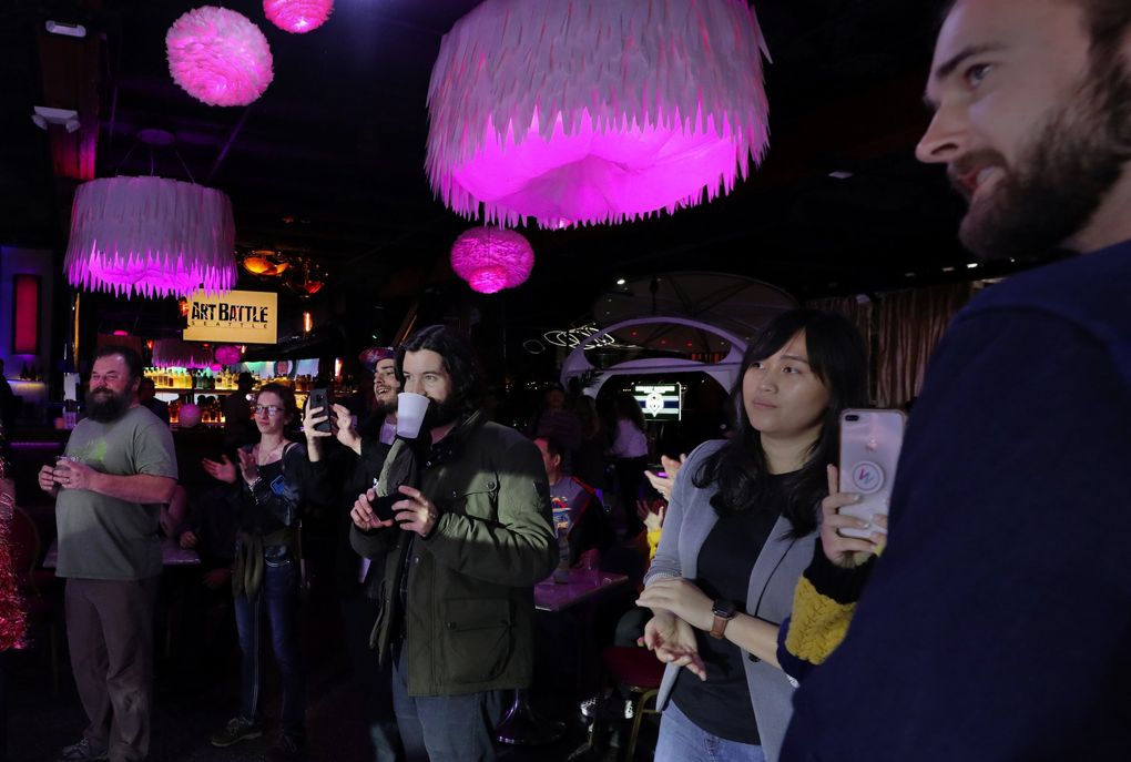 Audience members keep track of the artists’ progress during each timed round at Art Battle Seattle. (Alan Berner / Seattle Times)