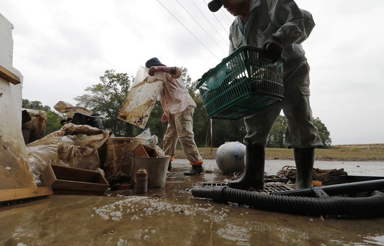 Residents Kazuo Saito, right, and Sumiko Saito clean up their home Monday, Oct. 14, 2019, in Kawagoe City, Japan. Typhoon Hagibis dropped record amounts of rain for a period in some spots, according to meteorological officials, causing more than 20 rivers to overflow. Some of the muddy waters in streets, fields and residential areas have subsided. But many places remained flooded, with homes and surrounding roads covered in mud and littered with broken wooden pieces and debris. (AP Photo/Eugene Hoshiko) TKKS101 TKKS101