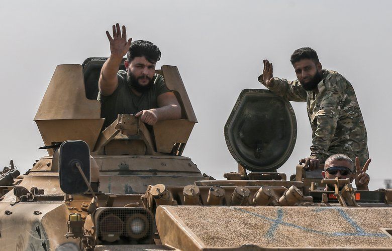 Turkish-backed Syrian opposition fighters on an armoured personnel carrier wave as they drive to cross the border into Syria, in Akcakale, Sanliurfa province, southeastern Turkey, Friday, Oct. 18, 2019. Fighting continued in a northeast Syrian border town at the center of the fight between Turkey and Kurdish forces early Friday, despite a U.S.-brokered cease-fire that went into effect overnight. (AP Photo/Emrah Gurel) XLP104 XLP104