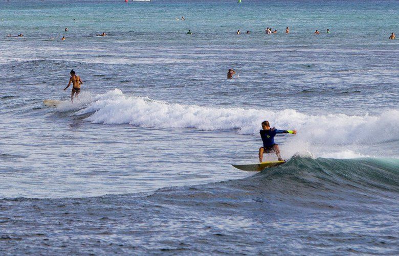 FILE – In this Nov. 4, 2014 file photo, surfers ride waves off Ala Moana Beach Park in Honolulu, with Diamond Head mountain in the background.AP Photo/Marco Garcia, File) HNL101
