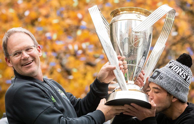 Seattle Sounders head coach Brian Schmetzer smiles at the crowd as Seattle Sounders midfielder Nicolas Lodeiro (10) kisses the MLS Cup during the celebratory Seattle Sounders parade in Seattle on November 12, 2019. 212095