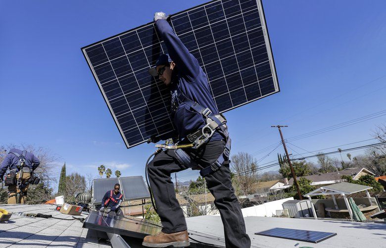 Alejandro DeLeon carries a solar panel as workers from home solar company Sunrun install a system on a home in Los Angeles. (Irfan Khan/Los Angeles Times/TNS) 1474959 1474959