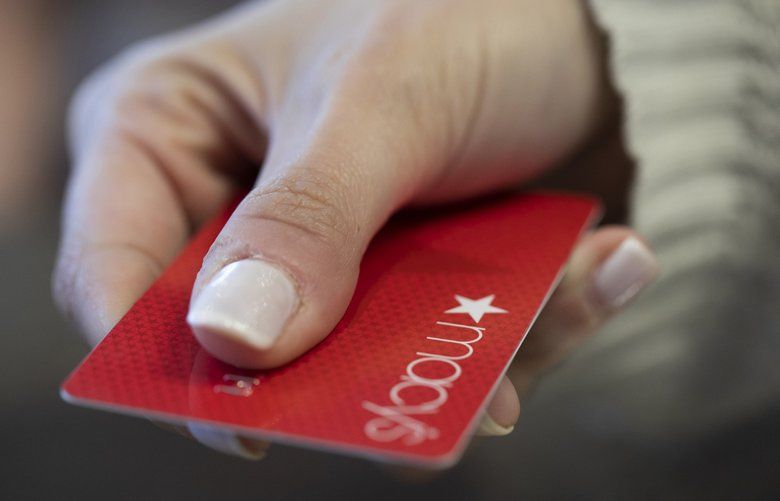 FILE – In this Aug. 11, 2019, file photo a woman holds a Macy’s card in New Orleans. Signups for retailer credit cards soar during the holidays. (AP Photo/Jenny Kane, File) NYBZ353 NYBZ353