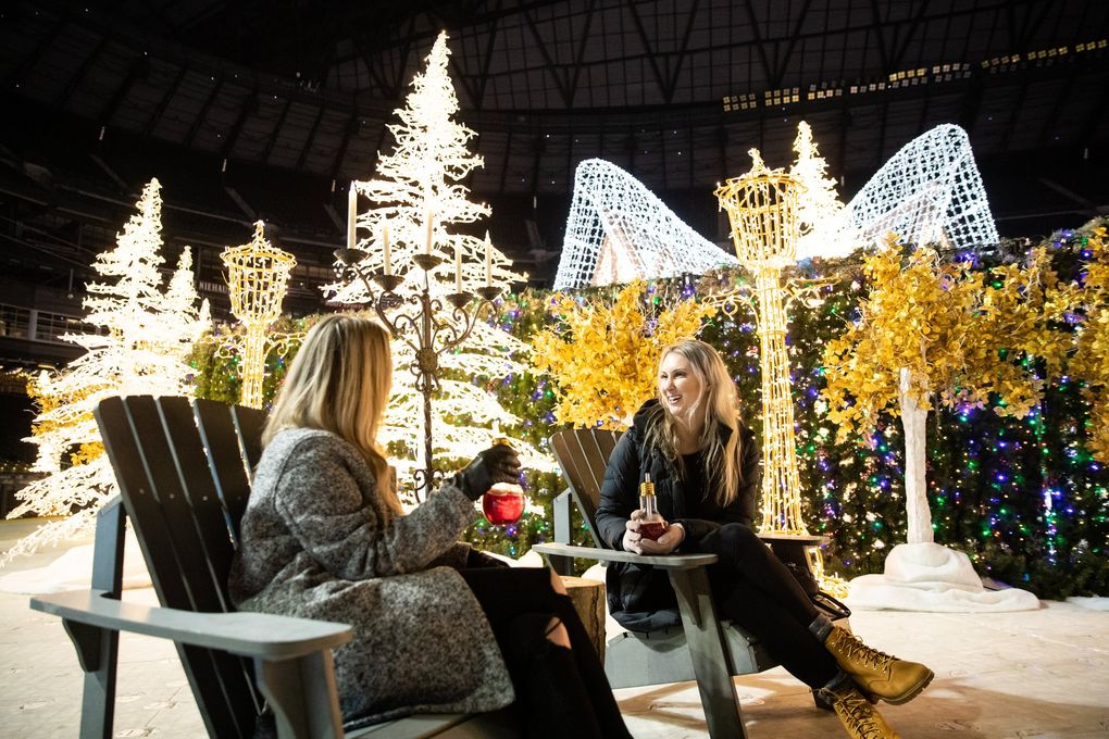 Robyn Stewart left, and Julie Jones sip their Enchant vodka-cranberry cocktails at Enchant Christmas. “It was $15 but it lights up” said Stewart. (Andy Bao / The Seattle Times)