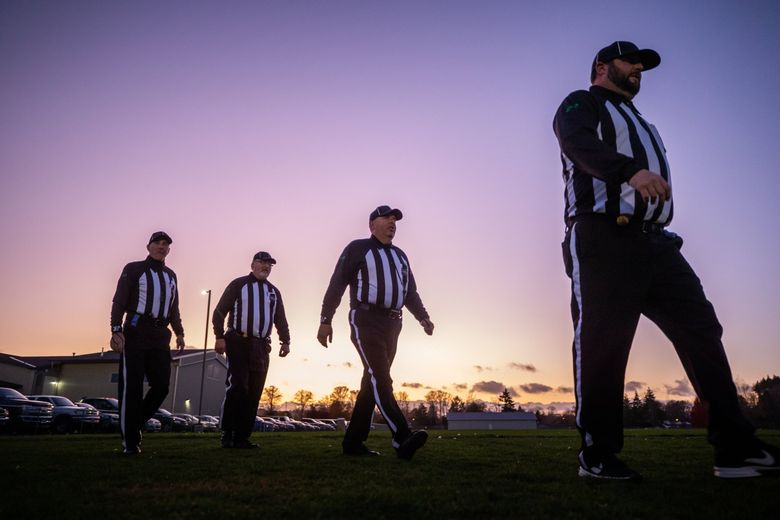 Football officials, from left, Eric Cheatley, Mike Kelley, Bryan Keatley and Jason Kelley take to the field before a Friday night football game between Adna High School and Onalaska High School last month. (Andy Bao / The Seattle Times)