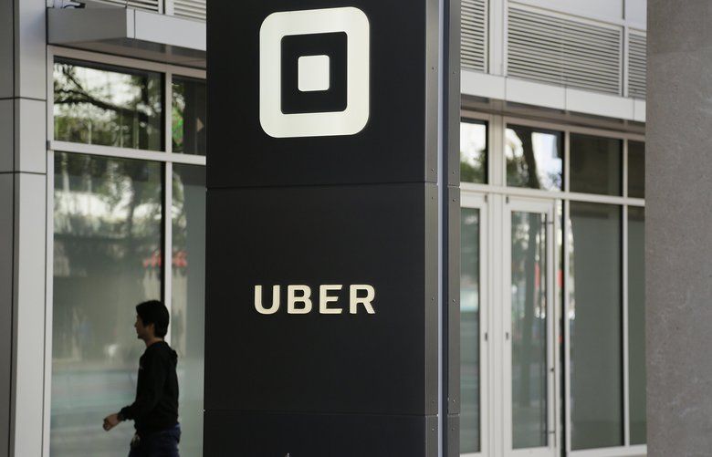 FILE- In this June 21, 2017, file photo a man walks into the building that houses the headquarters of Uber in San Francisco. (AP Photo/Eric Risberg, File) NYBZ461