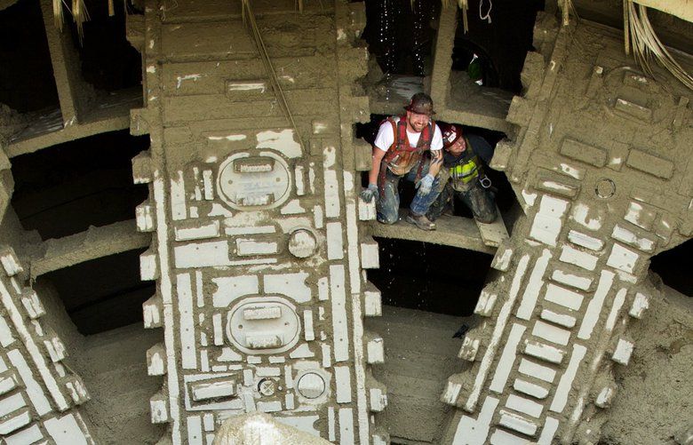 Tunneling crew members including Jake Chopic, left, with Seattle Tunnel Partners, emerges from the cutter head  after the giant tunneling machine Bertha broke into daylight as the giant drill chewed through the side of the disassembly vault and broke through the north portal wall on Tuesday April 4th, 2017 after nearly four years of boring underneath downtown Seattle.  201434