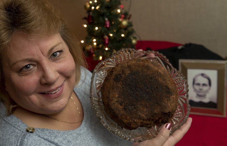 Julie Ruttinger, of Tecumseh, Mich., holds a 141-year-old fruitcake, Dec. 9, 2019, a family heirloom baked by her great-great-grandmother, Fidelia Ford, in 1878.  (David Guralnick/The Detroit News/TNS) 1517752 1517752